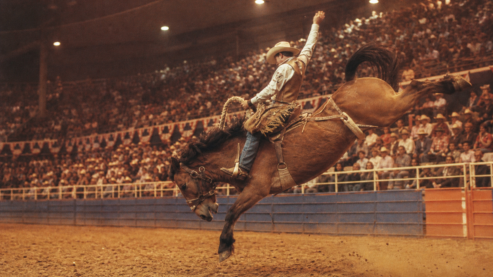 Vintage style saddle bronc rider in an old indoor rodeo arena for NFR history